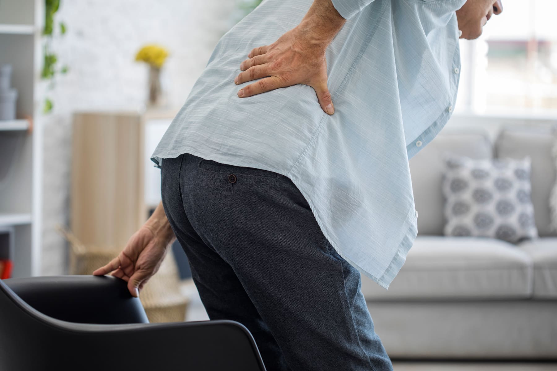 Problemas de la espalda en la tercera edad: un anciano se siente dolorido al levantarse del sillón