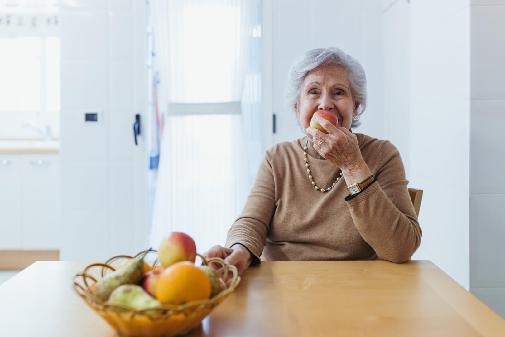 Persona mayor de 80 años comiendo una manzana