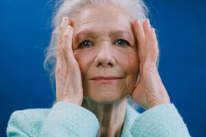 Mujer mayor se lleva las manos a la cabeza porque sufre de gota
