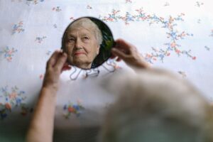 Mujer mayor se ve reflejada en el espejo: los telómeros influyen en el envejecimiento