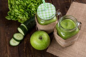 Plano cenital de batidos verdes, una manzana, espinacas y un pepino