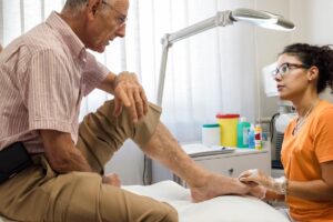 Hombre mayor es atendido por una podóloga que le explica cómo fortalecer las uñas de los pies