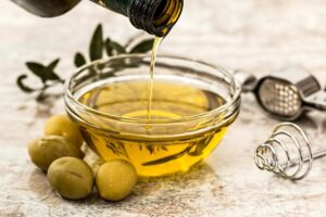 ¿Cómo fortalecer las uñas de los pies? Remedio casero: primer plano de un aceite de oliva vertido en un cacito