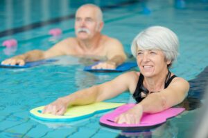 Un hombre y una mujer mayor realizando ejercicios de hidroterapia