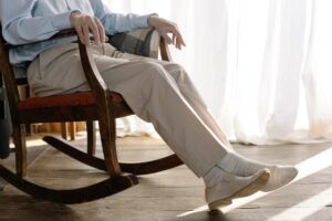 Hombre mayor tumbado en una silla mecedora con calzado para ancianos
