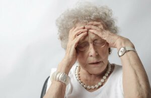 Mujer mayor llevándose las manos a la cabeza con actitud de malestar
