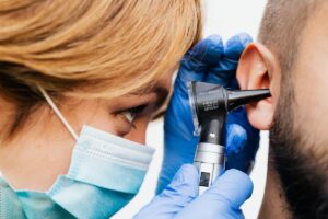Mujer otorrinonaringóloga, revisando el interior del oído de un paciente